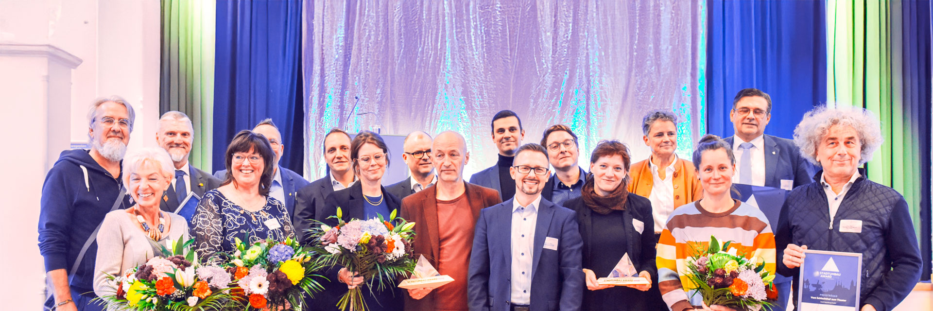 Ein Gruppenfoto der Preisträger des STADTUMBAU AWARDS 2025 auf der Bühne.
